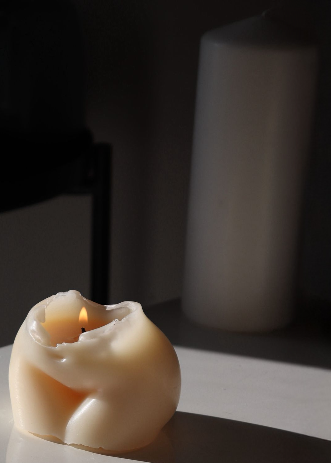 Candle in a bear-shaped holder on a reflective surface with a dark background