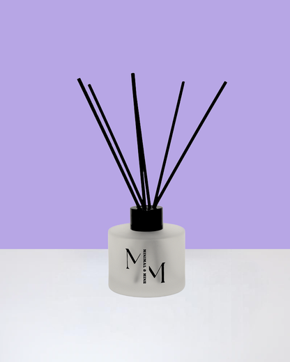 DOVES IN THE WIND REED DIFFUSER displayed against a purple background with black reeds.